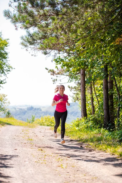 Mladá žena jogging na slunný den v přírodě — Stock fotografie