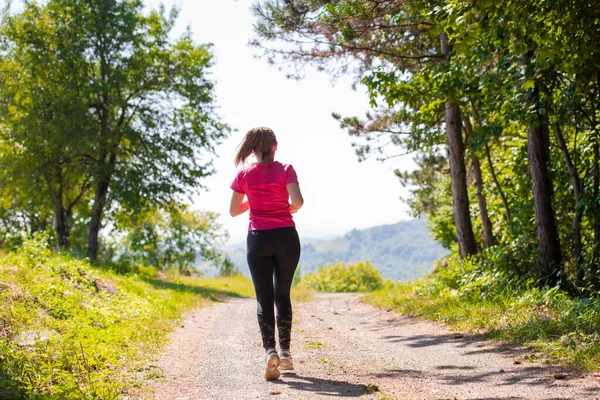 Jonge vrouw joggen op zonnige dag in de natuur — Stockfoto