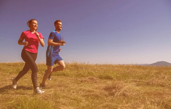 Młoda para jogging w słoneczny dzień na letniej górze — Zdjęcie stockowe