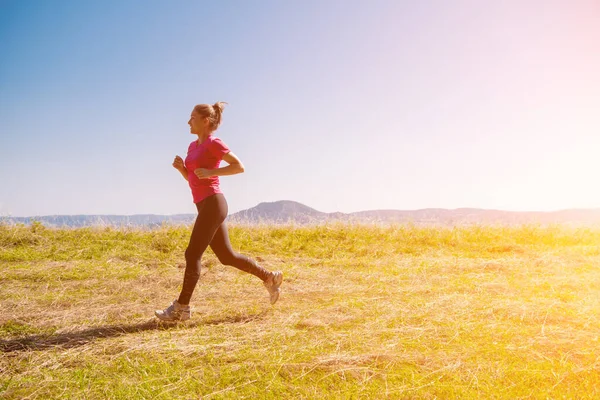 Młoda kobieta jogging w słoneczny dzień na letniej górze — Zdjęcie stockowe