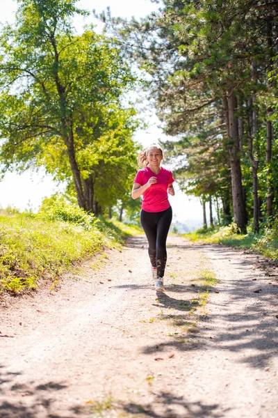 Młoda kobieta jogging w słoneczny dzień na łonie natury — Zdjęcie stockowe