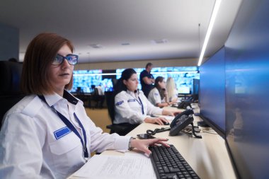 Güvenlik Veri Merkezi operatörleri bir CCTV izleme odasında birden fazla monitöre bakıyor. Sistem Kontrol Odası 'nda çalışan şüpheli aktiviteler için birden fazla ekran görüntülüyor.