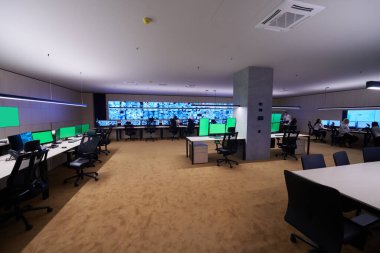 Güvenlik Veri Merkezi operatörleri bir CCTV izleme odasında birden fazla monitöre bakıyor. Sistem Kontrol Odası 'nda çalışan şüpheli aktiviteler için birden fazla ekran görüntülüyor.