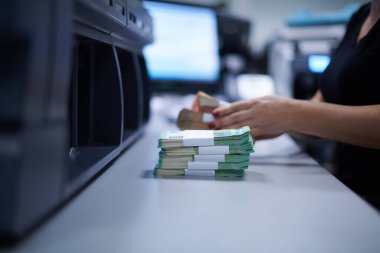 Banka çalışanları banka kasasında kağıt banknotları sıralarken ve sayarken para sayma makinesi kullanıyorlar. Bankada büyük miktarda para var.