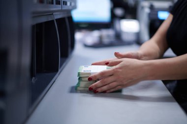 Banka çalışanları banka kasasında kağıt banknotları sıralarken ve sayarken para sayma makinesi kullanıyorlar. Bankada büyük miktarda para var.