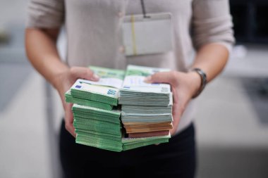 Banka çalışanları banka kasasında hesap yaparken elinde bir yığın kağıt banknot tutuyorlar. Bankada büyük miktarda para var.