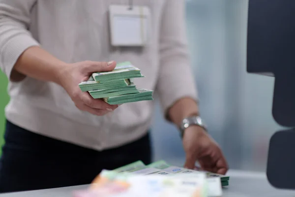 Bank employees using money counting machine while sorting and counting paper banknotes inside bank vault. Large amounts of money in the bank