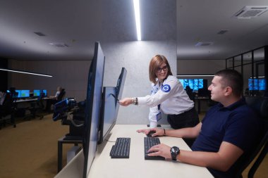 Güvenlik Veri Merkezi operatörleri bir CCTV izleme odasında birden fazla monitöre bakıyor. Sistem Kontrol Odası 'nda çalışan şüpheli aktiviteler için birden fazla ekran görüntülüyor.