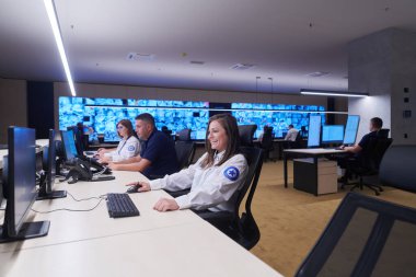 Güvenlik Veri Merkezi operatörleri bir CCTV izleme odasında birden fazla monitöre bakıyor. Sistem Kontrol Odası 'nda çalışan şüpheli aktiviteler için birden fazla ekran görüntülüyor.