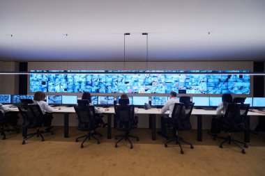 Güvenlik Veri Merkezi operatörleri bir CCTV izleme odasında birden fazla monitöre bakıyor. Sistem Kontrol Odası 'nda çalışan şüpheli aktiviteler için birden fazla ekran görüntülüyor.