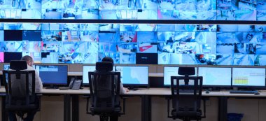 Güvenlik Veri Merkezi operatörleri bir CCTV izleme odasında birden fazla monitöre bakıyor. Sistem Kontrol Odası 'nda çalışan şüpheli aktiviteler için birden fazla ekran görüntülüyor.