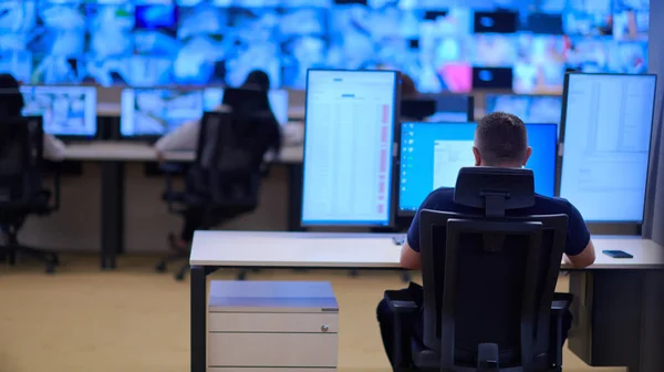 Male security operator working in a data system control room offices Technical Operator Working at  workstation with multiple displays, security guard working on multiple monitors  Male computer operator monitoring from a security center