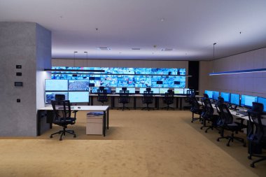 Büyük, modern güvenlik kontrol odasının içi boş, birden fazla ekranı olan çalışma istasyonu, güvenlik veri merkezindeki izleme odası boş ofis, masa ve ana CCTV veri merkezindeki sandalyeler.