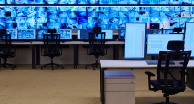 Büyük, modern güvenlik kontrol odasının içi boş, birden fazla ekranı olan çalışma istasyonu, güvenlik veri merkezindeki izleme odası boş ofis, masa ve ana CCTV veri merkezindeki sandalyeler.