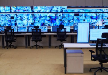 Büyük, modern güvenlik kontrol odasının içi boş, birden fazla ekranı olan çalışma istasyonu, güvenlik veri merkezindeki izleme odası boş ofis, masa ve ana CCTV veri merkezindeki sandalyeler.