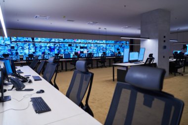Büyük, modern güvenlik kontrol odasının içi boş, birden fazla ekranı olan çalışma istasyonu, güvenlik veri merkezindeki izleme odası boş ofis, masa ve ana CCTV veri merkezindeki sandalyeler.