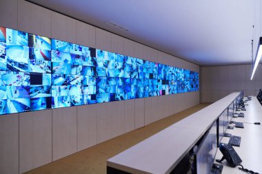 Büyük, modern güvenlik kontrol odasının içi boş, birden fazla ekranı olan çalışma istasyonu, güvenlik veri merkezindeki izleme odası boş ofis, masa ve ana CCTV veri merkezindeki sandalyeler.