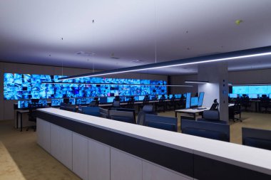 Büyük, modern güvenlik kontrol odasının içi boş, birden fazla ekranı olan çalışma istasyonu, güvenlik veri merkezindeki izleme odası boş ofis, masa ve ana CCTV veri merkezindeki sandalyeler.