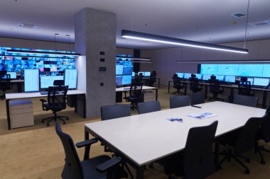 Büyük, modern güvenlik kontrol odasının içi boş, birden fazla ekranı olan çalışma istasyonu, güvenlik veri merkezindeki izleme odası boş ofis, masa ve ana CCTV veri merkezindeki sandalyeler.