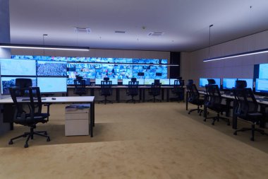 Büyük, modern güvenlik kontrol odasının içi boş, birden fazla ekranı olan çalışma istasyonu, güvenlik veri merkezindeki izleme odası boş ofis, masa ve ana CCTV veri merkezindeki sandalyeler.