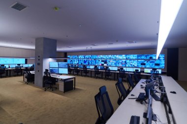 Büyük, modern güvenlik kontrol odasının içi boş, birden fazla ekranı olan çalışma istasyonu, güvenlik veri merkezindeki izleme odası boş ofis, masa ve ana CCTV veri merkezindeki sandalyeler.