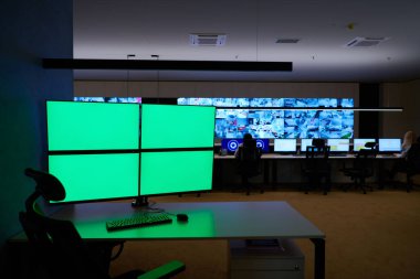 Boş yeşil ekranlı büyük modern güvenlik kontrol odasının içi, birden fazla ekranı olan çalışma istasyonu, güvenlik veri merkezindeki izleme odası boş ofis, masa ve ana CCTV veri merkezindeki sandalyeler.