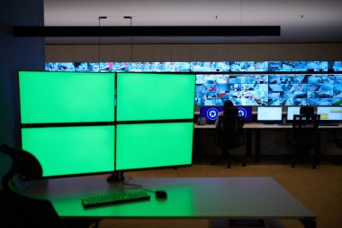Boş yeşil ekranlı büyük modern güvenlik kontrol odasının içi, birden fazla ekranı olan çalışma istasyonu, güvenlik veri merkezindeki izleme odası boş ofis, masa ve ana CCTV veri merkezindeki sandalyeler.