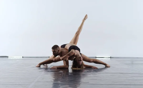 ブラックタイツの若いアスレチックダンスパートナーのカップルがアクロバティックな要素を作る現代的なスタイルのバレエを上演白い背景の前で芸術パフォーマンスのスポーティバレエダンサーのカップル — ストック写真