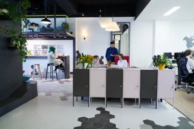 Modern açık planlama ofisinin dinlenme alanının tadını çıkarırken farklı şeyler yaparak işten izin alan çok ırklı iş adamları.