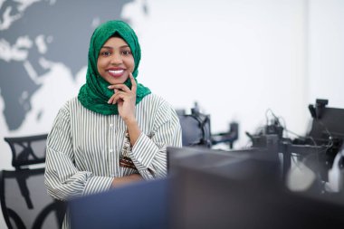 Modern açık plan başlangıç ofisinde duran yeşil tesettürlü Müslüman Afrikalı kadın yazılım geliştirici portresi