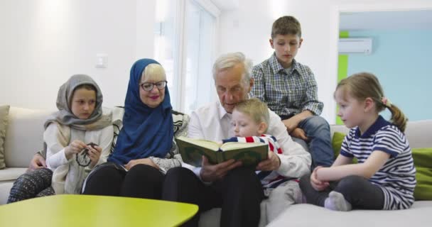 Ovanifrån av moderna muslimska morföräldrar med barnbarn readin — Stockvideo