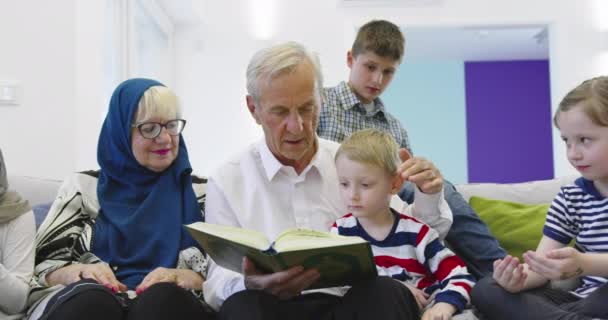 Верхний вид современных мусульманских бабушки и дедушки с внуками читать в — стоковое видео