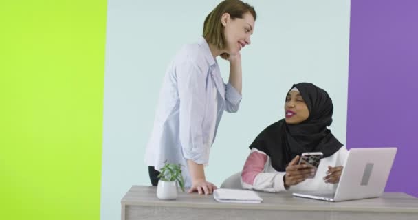 Diversidad Reunión de mujeres étnicas en el cargo. Chica sonriente en Hijab trabajando en el ordenador portátil, rubia mirando la pantalla. — Vídeos de Stock