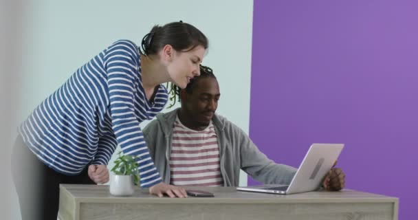Pozytywnie uśmiechnięty mężczyzna i kobieta w pobliżu miejsca pracy z laptopem współpracującym w biurze — Wideo stockowe