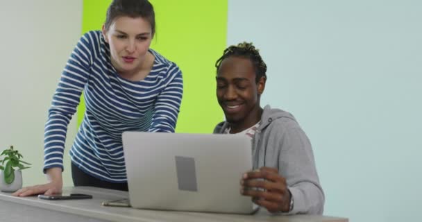 Pozytywnie uśmiechnięty mężczyzna i kobieta w pobliżu miejsca pracy z laptopem współpracującym w biurze — Wideo stockowe