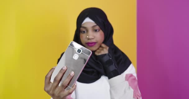 穿着传统服装的穆斯林妇女在明亮的背景下使用智能手机 — 图库视频影像