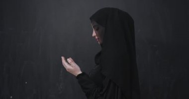 Güzel Müslüman kadın portresi, tesettürlü, geleneksel dua eden, modern İslami modayı ve Ramazan Kareem kavramını temsil eden siyah karatahta izole edilmiş dua eden bir jest içinde.