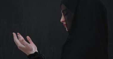 Güzel Müslüman kadın portresi, tesettürlü, geleneksel dua eden, modern İslami modayı ve Ramazan Kareem kavramını temsil eden siyah karatahta izole edilmiş dua eden bir jest içinde.
