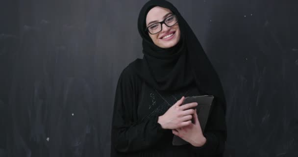 伝統的な祈りを捧げるヒジャーブのファッショナブルなドレスを着た美しいイスラム教徒の女性の肖像は 現代のイスラム教徒のファッションとラマダーン カレームの概念を表す黒い黒板の背景に隔離された祈りのジェスチャーで手を維持します — ストック動画