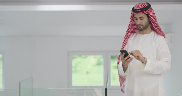 Молодой Современный Мусульманский Арабский Бизнесмен Традиционной Одежде Используя Смартфон Дома — стоковое видео