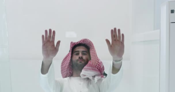 Мусульманин в традиционной одежде молится на стеклянном полу перед ужином — стоковое видео
