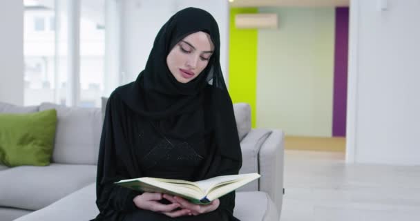 斋月期间 年轻的穆斯林妇女在家里的花坛晚宴前 在沙发上朗诵 古兰经 — 图库视频影像