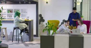 Çok ırklı bir girişim ekibi, modern parlak ofis içi beyin fırtınası, başlangıç ofisinde dizüstü bilgisayar ve tablet bilgisayar üzerine çalışıyor