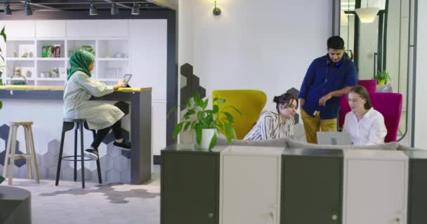 Çok ırklı bir girişim ekibi, modern parlak ofis içi beyin fırtınası, başlangıç ofisinde dizüstü bilgisayar ve tablet bilgisayar üzerine çalışıyor — Stok video