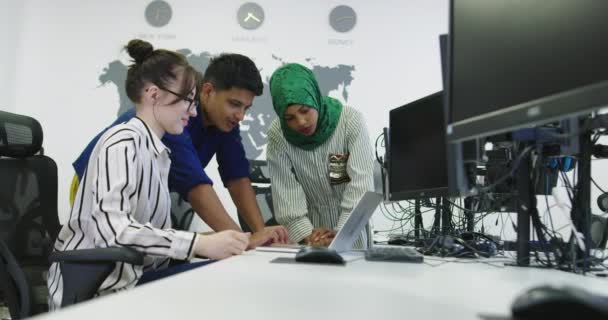 Grupo de jóvenes compañeros de trabajo multiétnicos vestidos casualmente trabajando juntos centrado en el monitor de la computadora en la oficina de inicio — Vídeo de stock