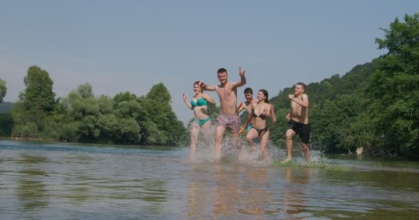 Sommar glädje grupp glada vänner att ha kul när du springer och stänk på floden — Stockvideo