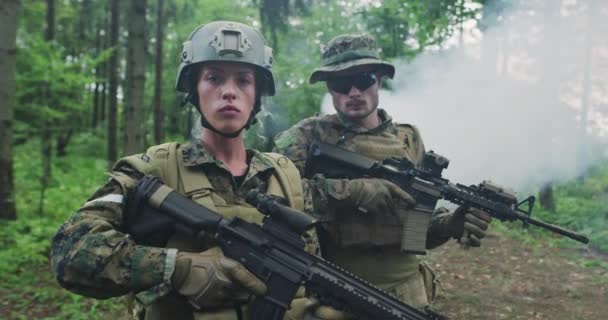 Squad of soldiers patrolling across the forest area, team with male and female soliders in dense forest with smoke in backgorund — Stock Video