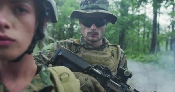 Trupp av soldater patrullerar över skogsområdet, team med manliga och kvinnliga soliders i tät skog med rök i backgorund — Stockvideo