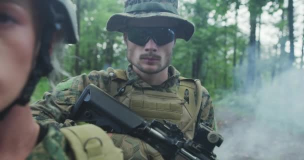 Oddíl vojáků hlídkujících přes les, tým s mužskými a ženskými vojáky v hustém lese s kouřem v pozadí — Stock video