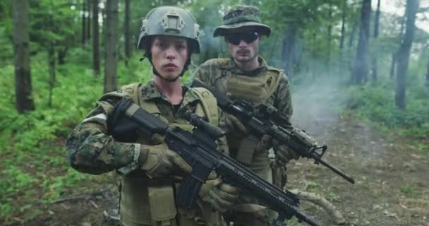 Katonákból álló osztag járőrözik az erdőterületen, egy csapat férfi és női katonával sűrű erdőben, füsttel a hátsókertben. — Stock videók